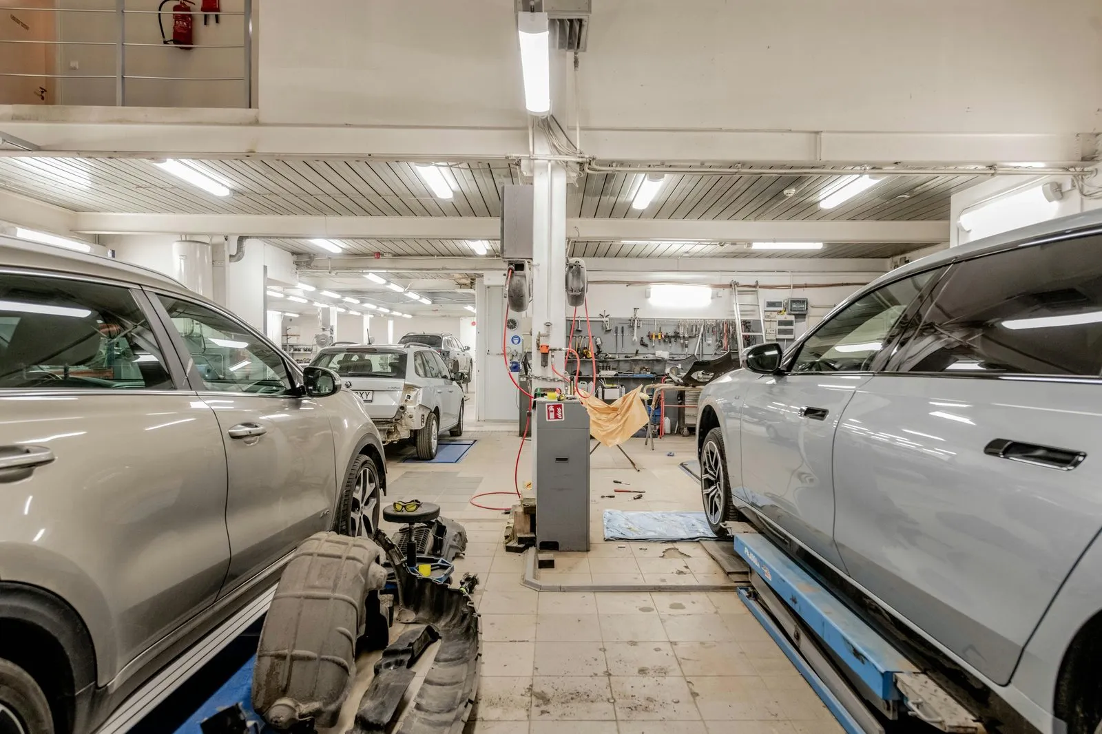 Oficina mecânica com carros em manutenção, elevador automotivo e ferramentas no fundo